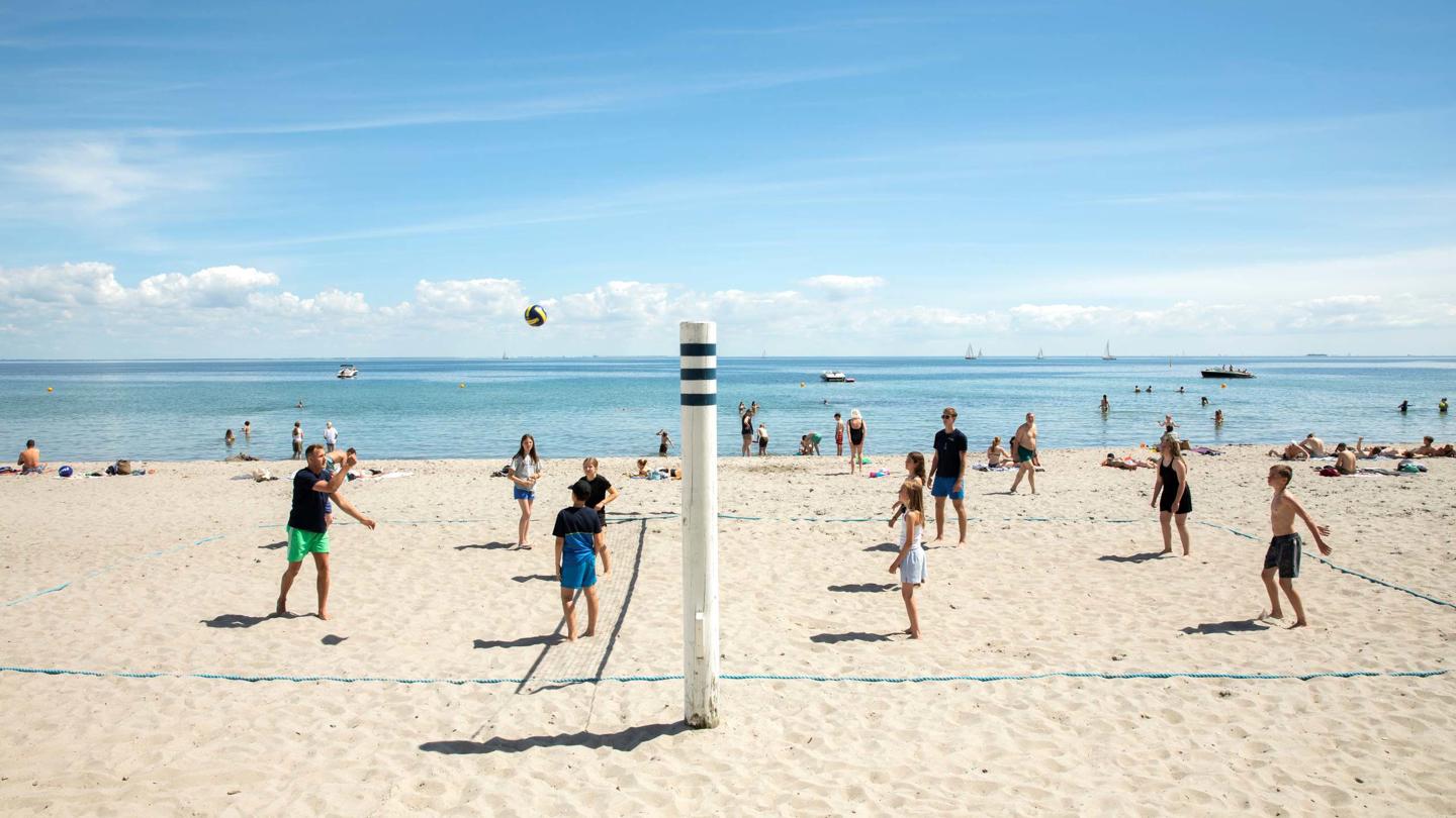 Børn og unge, der spiller Volleyball på stranden