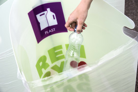 Fotografi af hånd, der kommer en plastflaske i en af Eventkittets beholdere.